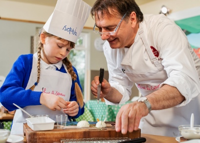Image: Courtesy of Paul Wilkinson Photographt - Raymond Blanc cooking with a pupil from Haddenham St Mary's school