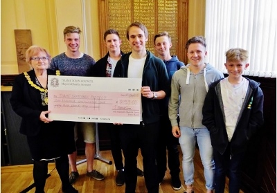 Jeannette Matelot Green and Corin Rea hold up the cheque, surrounded by smiling skaters